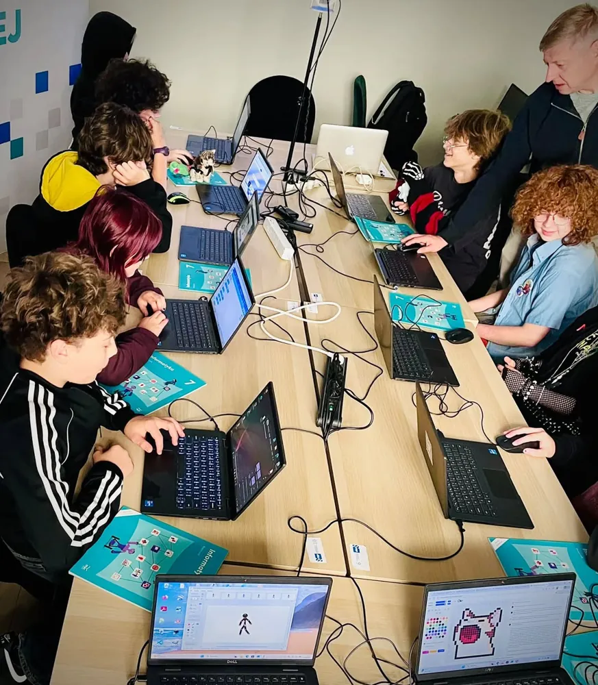 Starsi uczniowie przy laptopach na zajęciach z programowania