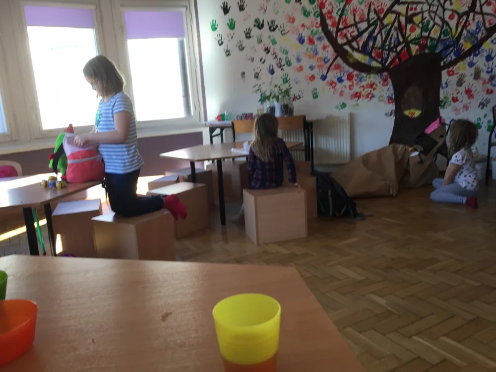Ściana z namalowanym drzewem, którego liście to odciski dziecięcych dłoni