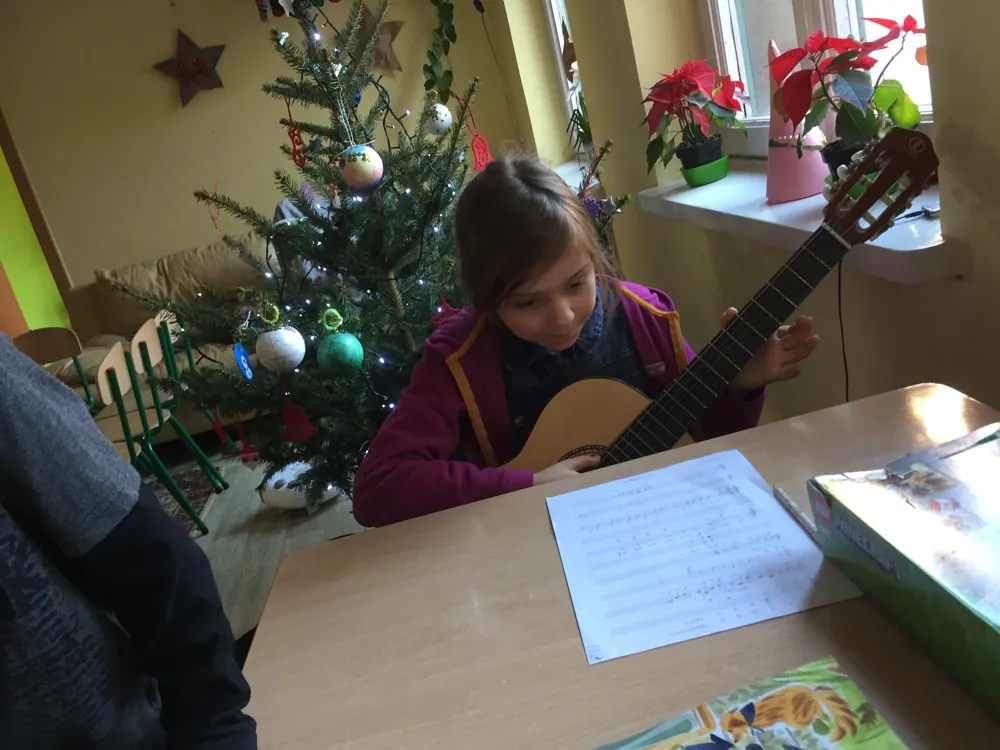 Dziewczynka ćwiczy na gitarze przy choince