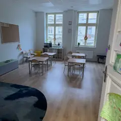 Jasna sala z dużymi oknami i stolikami dla małych grup