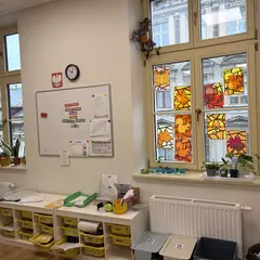 Sala z żółtymi pojemnikami uczniów i jesiennymi witrażami w oknie
